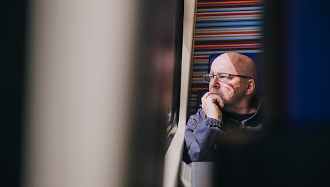 An older man sitting alone on a train in Amsterdam.