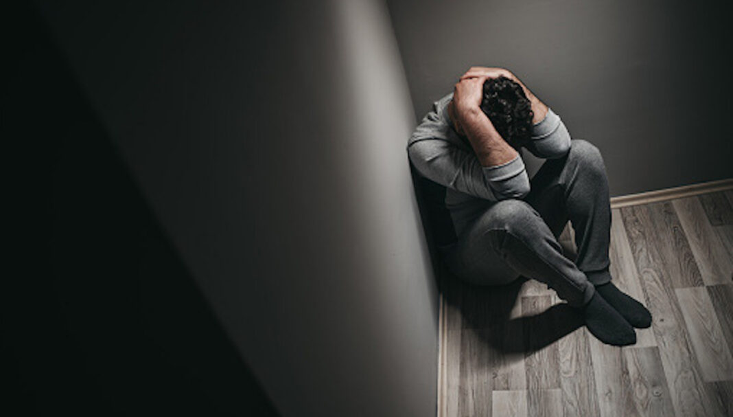 Young depressed man sitting on floor