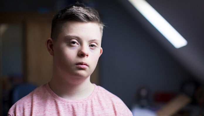 A boy with down syndrome poses for a headshot.