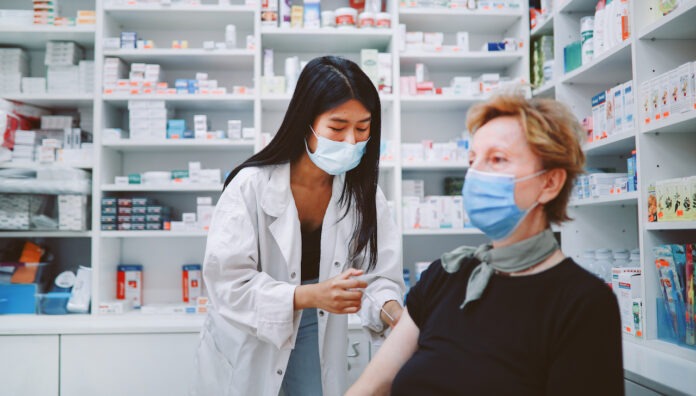 Asian nurse giving flu vaccine to a senior patient