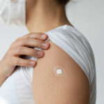 Young woman with Covid-19 vaccine has a patch or adhesive bandage on her arm.